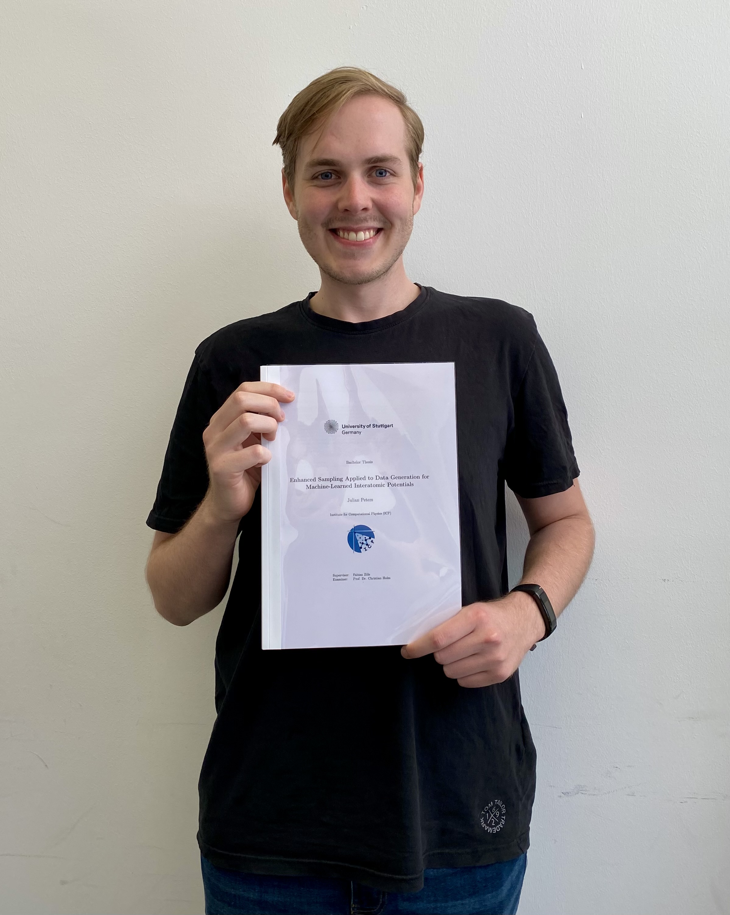 Julian Peters smiling while showing his BSc thesis